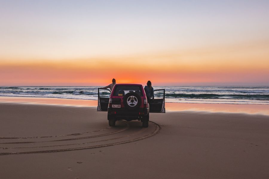 people in 4wd on the beach at sunset on K'gari