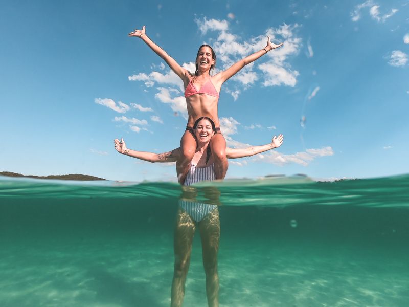 two girls posing in the blue waters of a K'gari lake