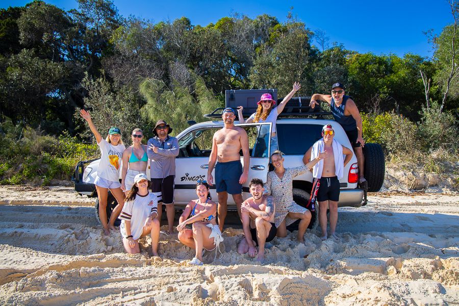 group of backpackers posing in front of a 4wd car