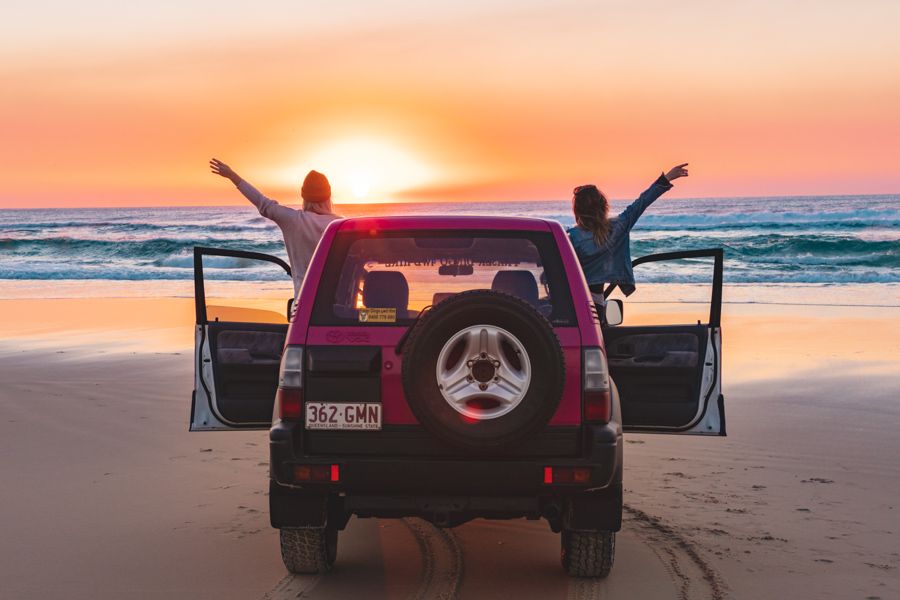 people in 4wd on beach at sunrise