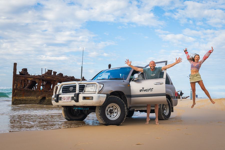 travellers posing next to a 4wd on kgari beach
