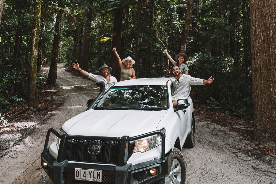 people posing in a white 4wd vehicle kgari rainforest