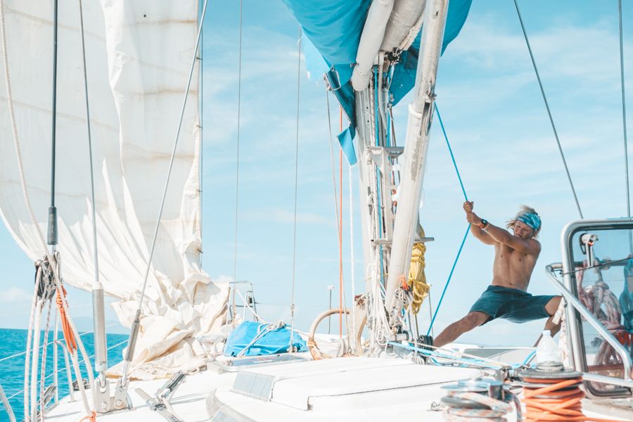 A man pulling ropes on a sailing boat