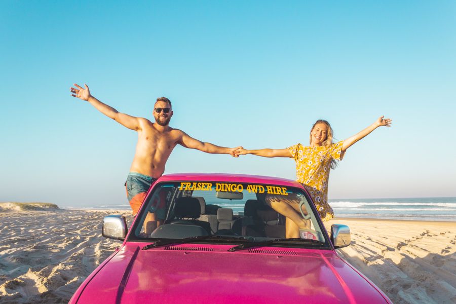 two people smiling in a pink 4WD Hire on K'gari