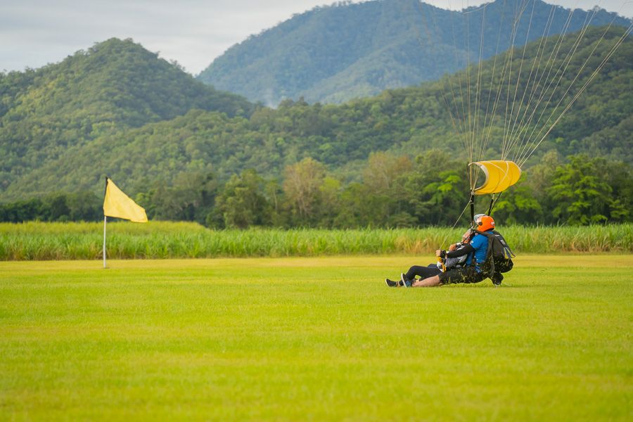 A skydiver landing on the grass with the parachute behind