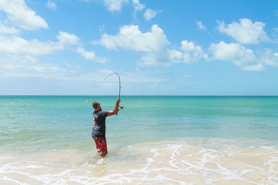 man fishing in the bright blue ocean off the coast of K'gari