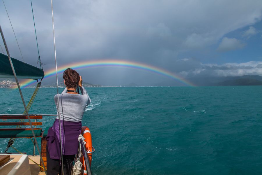 Woman taking photo of rainbow under stormy skies