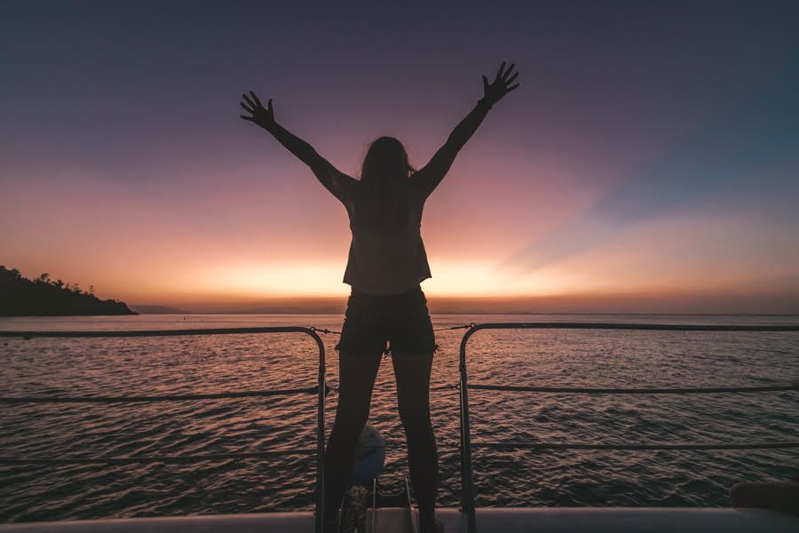 Woman holding arms up to sunrise