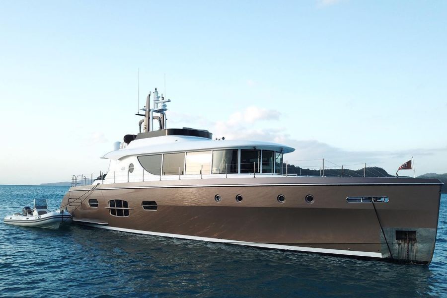 A grey and white superyacht anchored in blue water