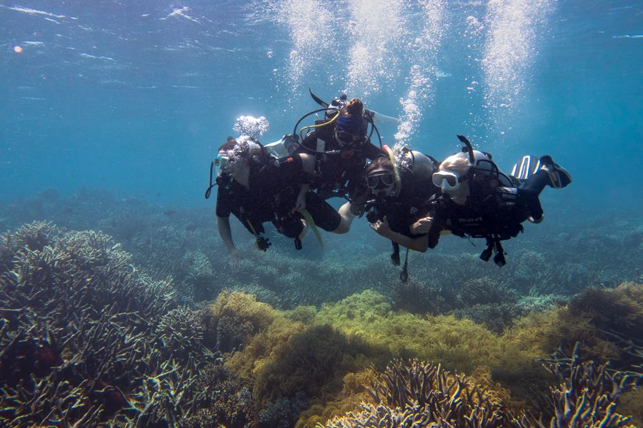 Trio of divers posing for camera underwater 