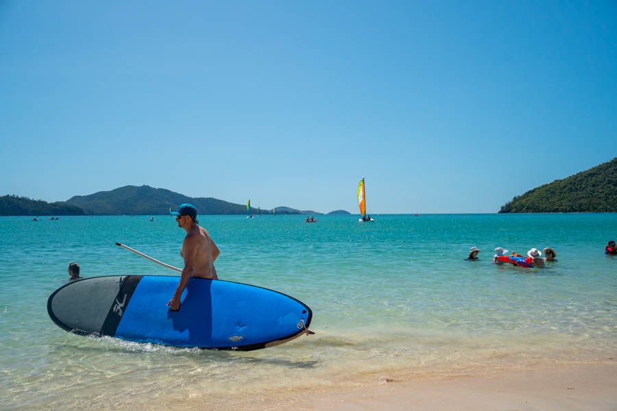 man holding paddleboard on hamilton island whitsundays