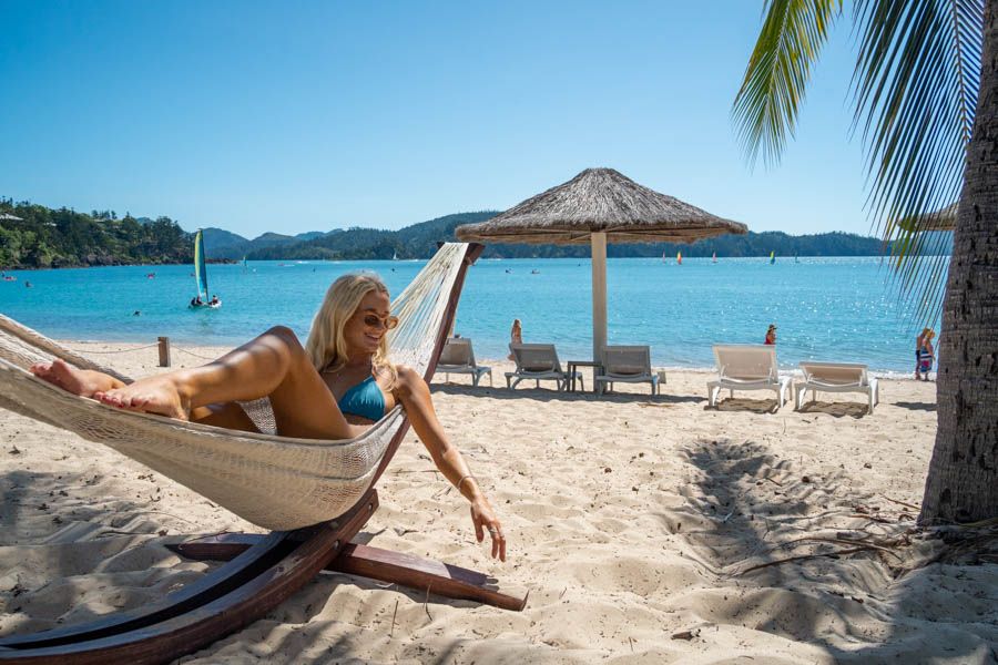 girl lounging in a hammock on catseye beach hamilton island