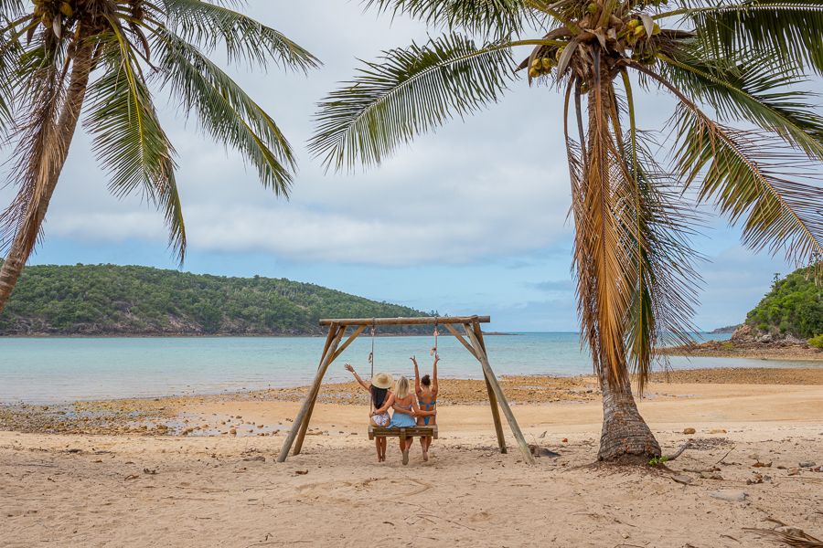 girls posing on beach swing on hamilton island whitsundays