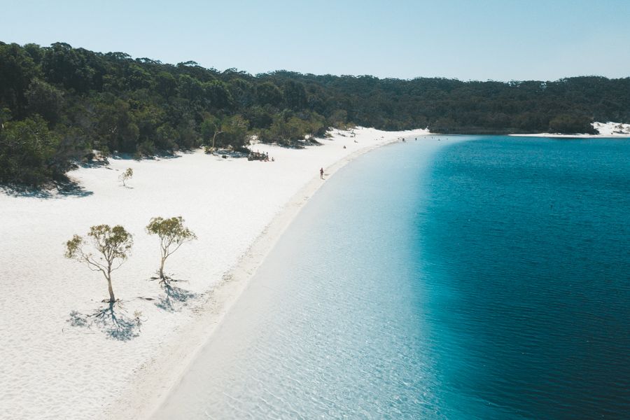 person walking along the white sandy shores of Lake McKenzie