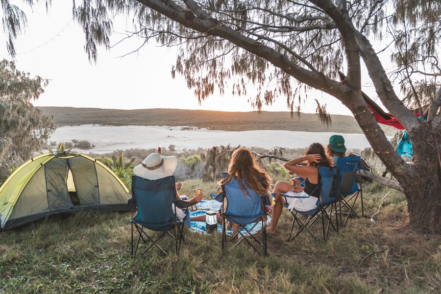 Travellers relaxing in camping chairs at a campsite on K'gari