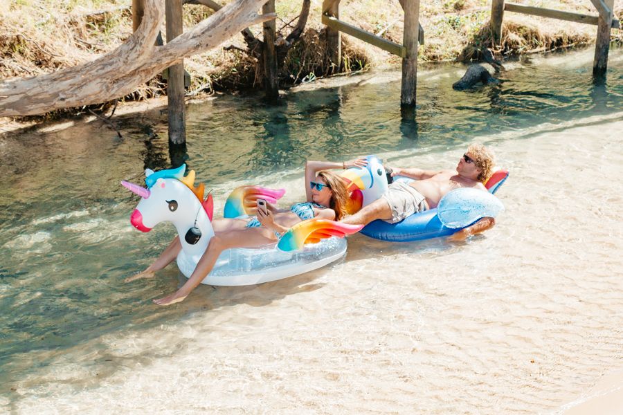 couple floating down Eli Creek in colorful floats