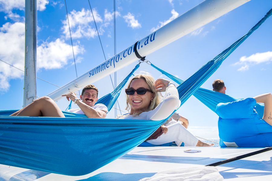 Whitsundays a man and a woman hanging in blue hammocks on a boat