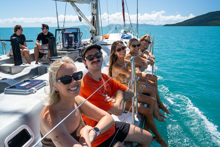 A group of young people sitting over the edge of a sailing boat