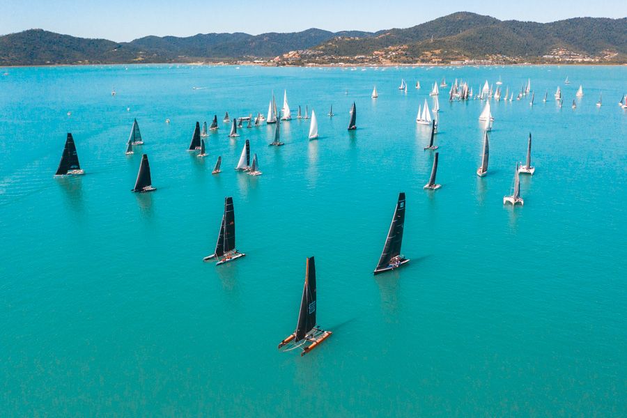 A fleet of sailing boats with their sails up in blue waters