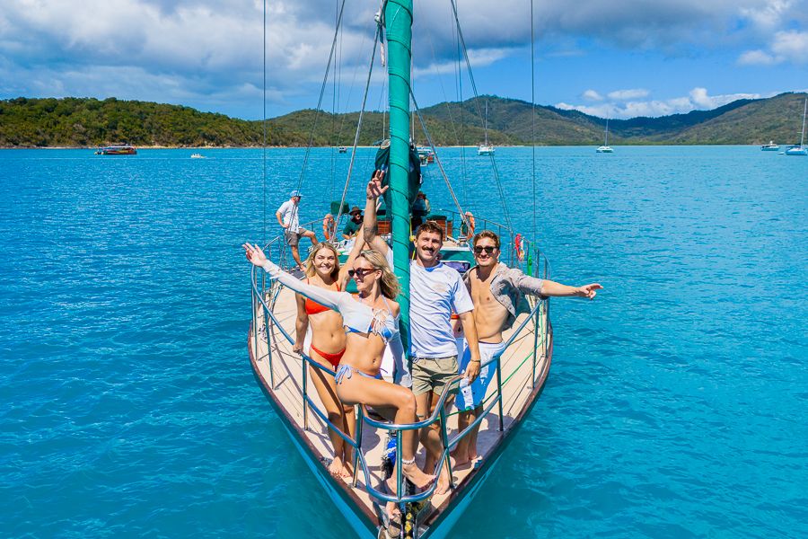 people on the front of a sailboat in the whitsundays