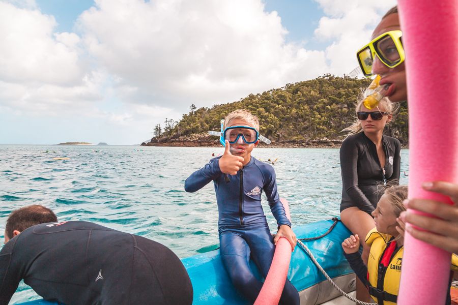 A young kid in a stinger suit snorkelling in the Whitsundays