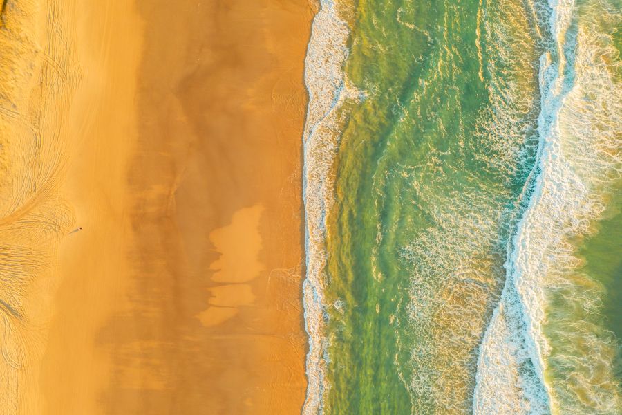 aerial view of waves rushing onto shore on K'gari