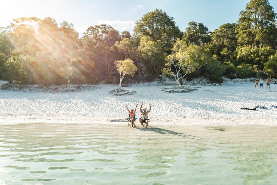 couple posing in chairs on the shores of Lake Mckenzie