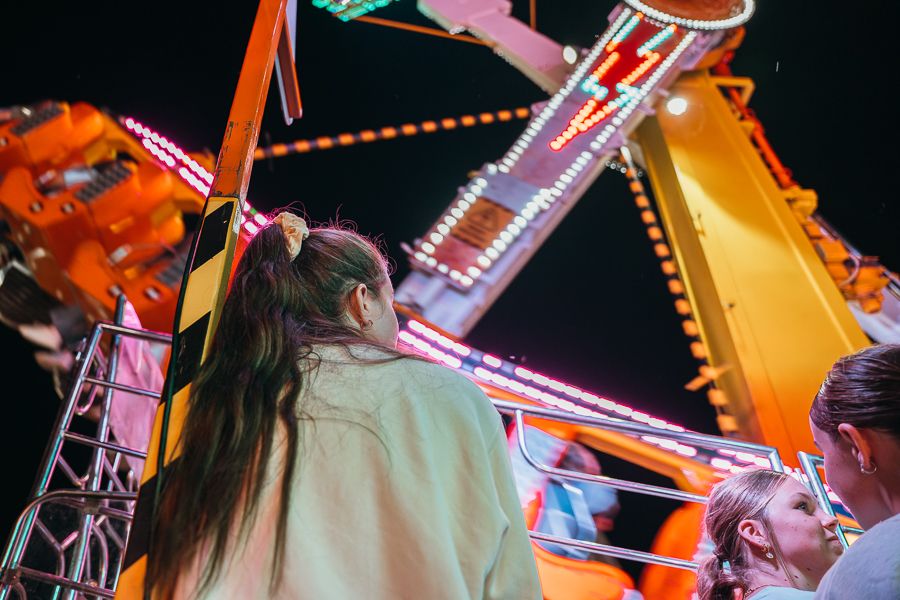 girl looking at colourful games and rides at a show