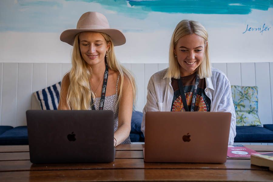 two girls typing on laptops inside a cafe