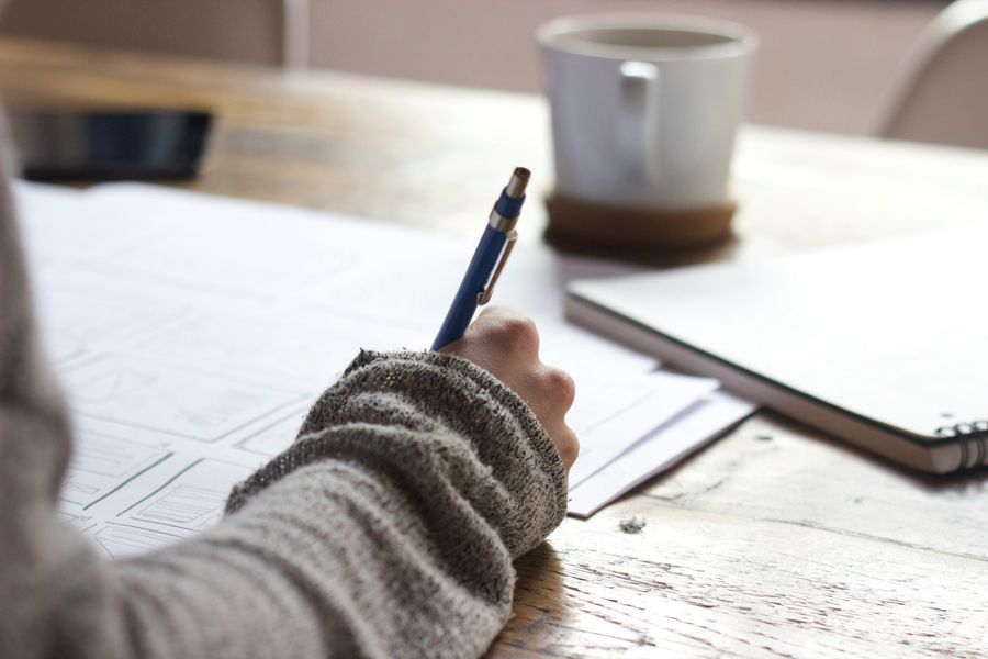 close up of person writing at a desk with a pen