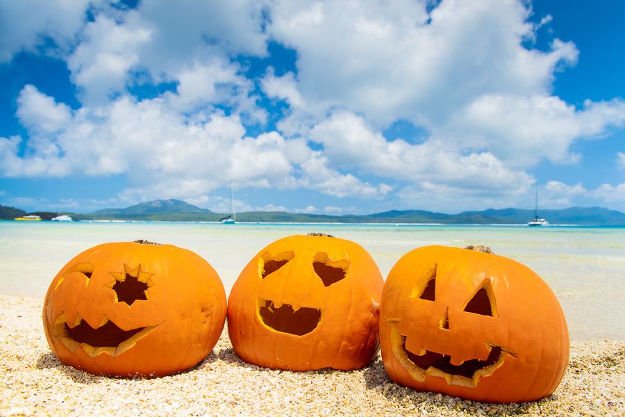 Halloween in Airlie Beach three pumpkins with carved out faces sitting in sand
