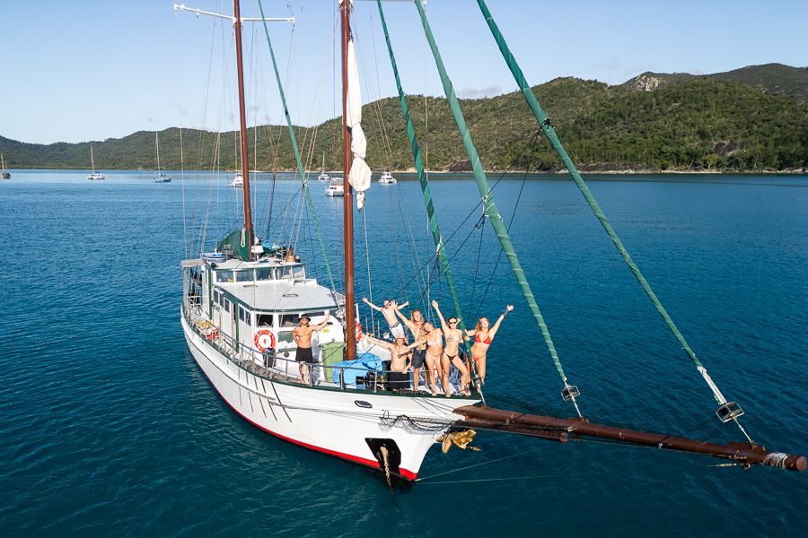A drone shot of people waving on a sailing boat