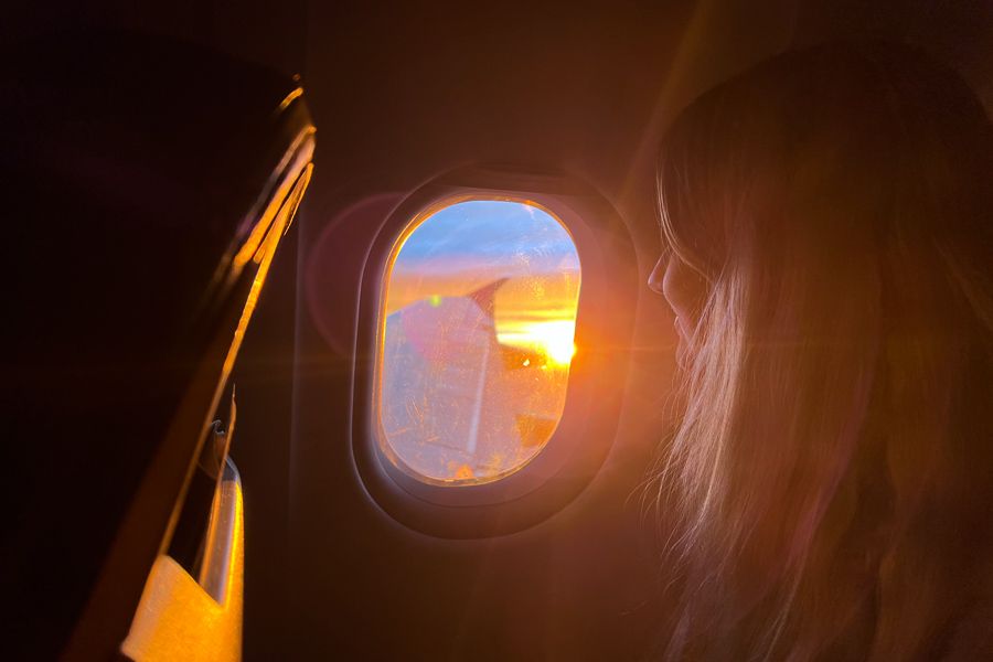 girl looking out plane window at a sunrise over australia