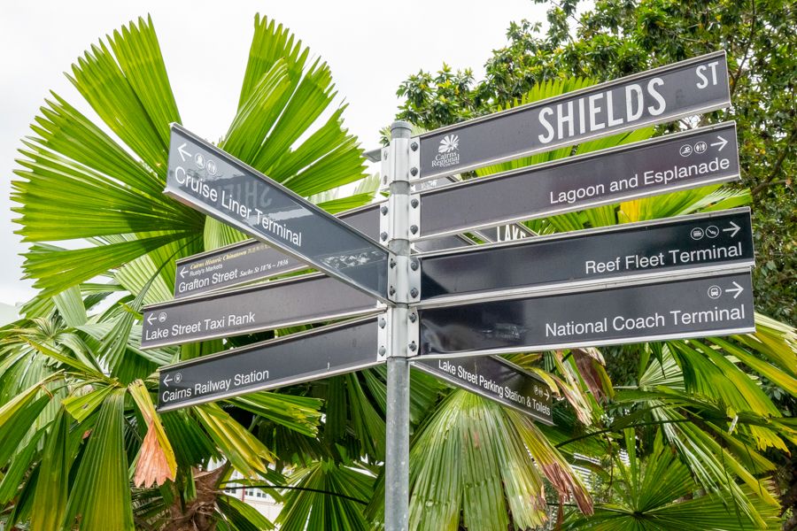 city street signs in front of greenery in cairns