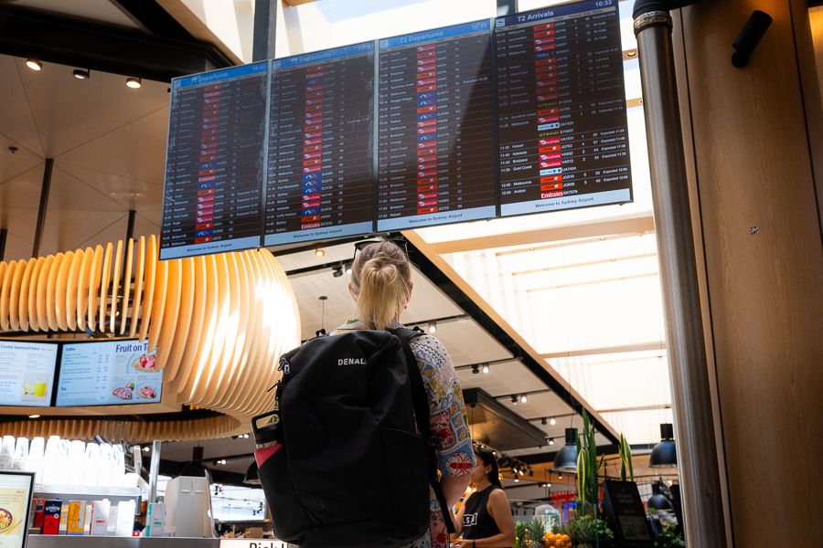 Sydney Airport girl looking at a departures board in sydney airport