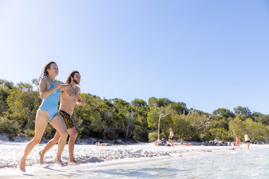 A couple running along the beach on K'gari (Fraser Island)