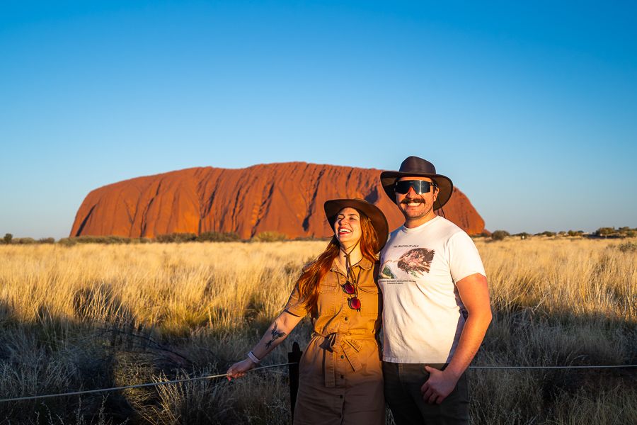 couple smiling in front of uluru australia