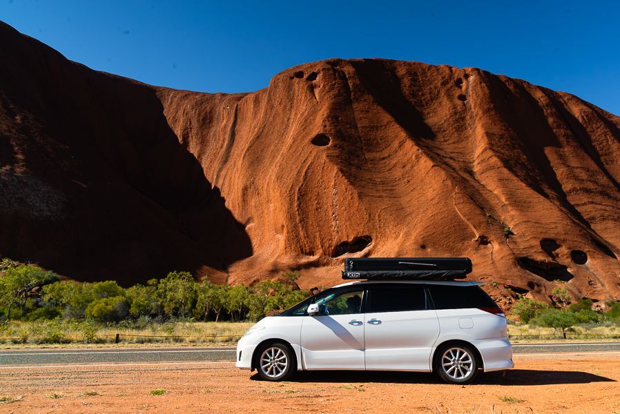 van with camping top parked in front of uluru australia