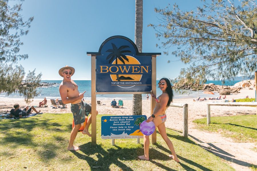 people smiling in front of bowen sign australia
