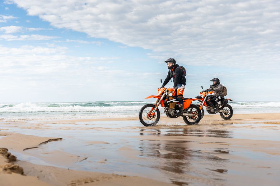 people racing motorbikes along the sand australia