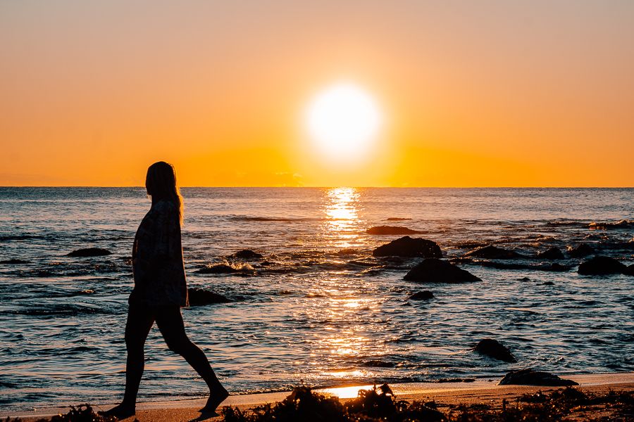 girl walking along bondi beach at sunrise