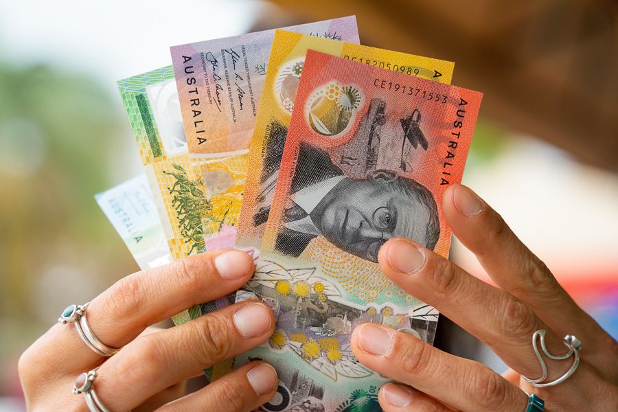 person holding up selection of colourful australian bills