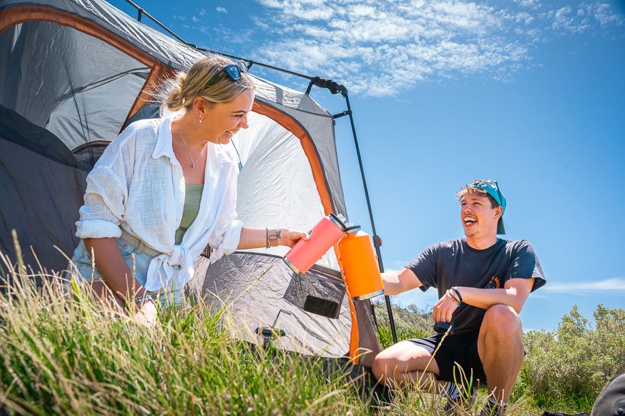 couple camping and drinking water in whitsundays