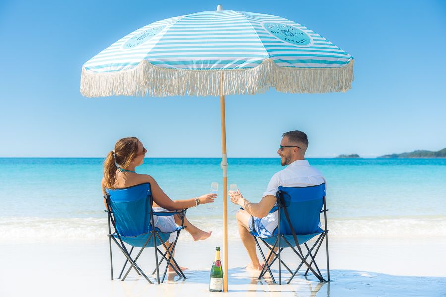 couple relaxing under an umbrella on whitehaven beach