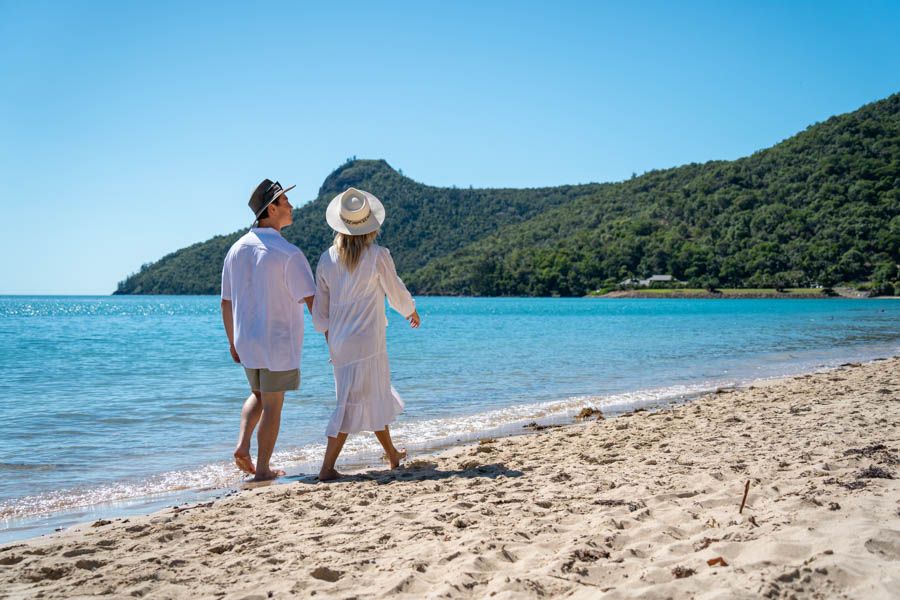 couple walking along the sand at catseye beach