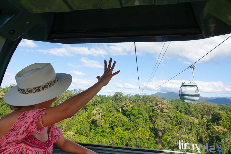 A girl waving at another cable on the Skyrail cableway