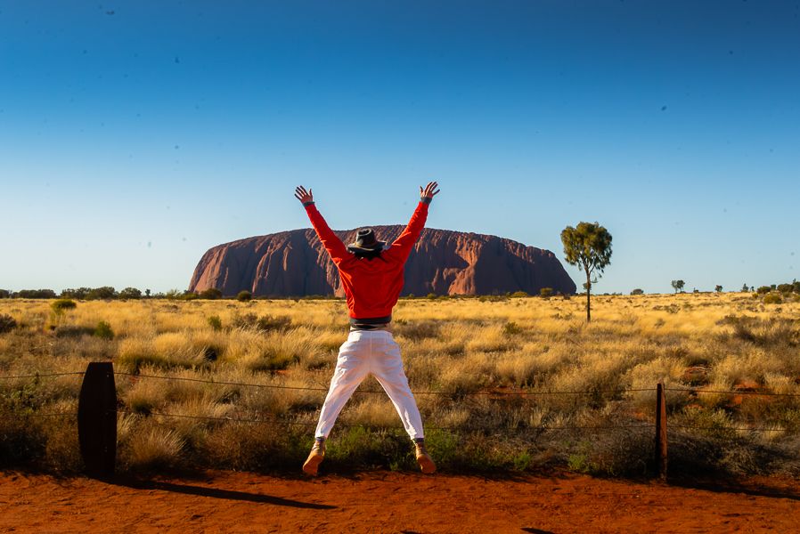 man jumping in front of uluru in the outback