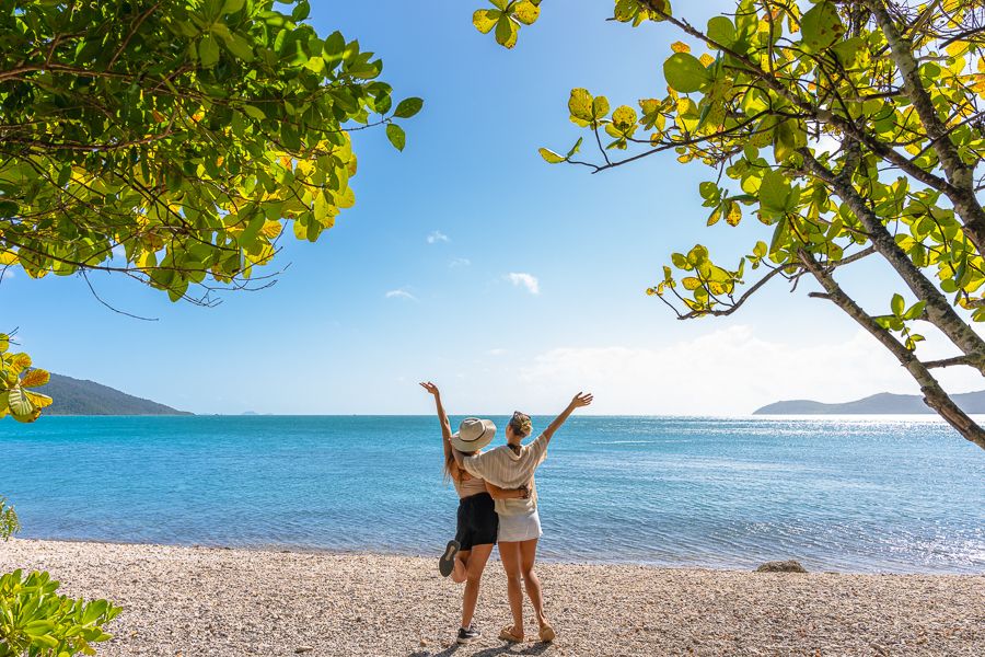 Two women with their arms in the air on a beach