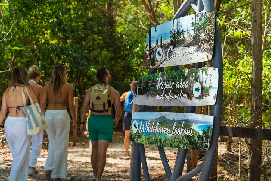 A group of people walking past a sign that says 'whitehaven'