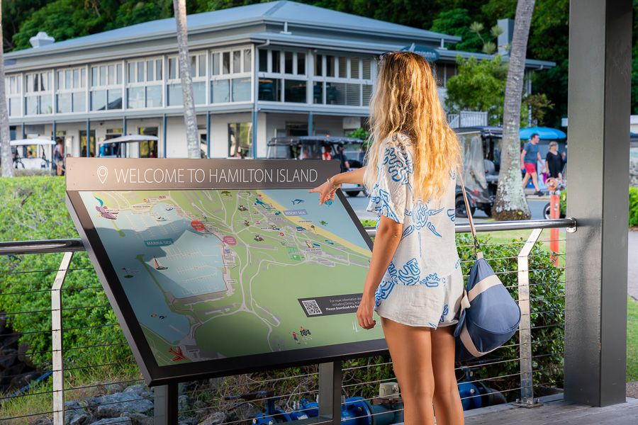 girl reading the hamilton island map and welcome sign